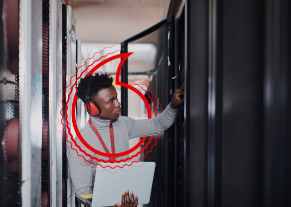 Shot of a young handsome man wearing headphones and using a laptop at work in a server room